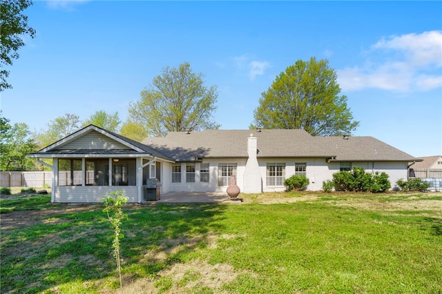 back of house featuring a lawn, a sunroom, fence, and a patio