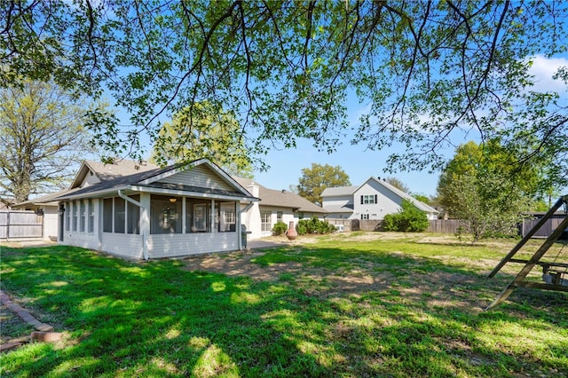 back of house featuring a fenced backyard, a sunroom, and a yard
