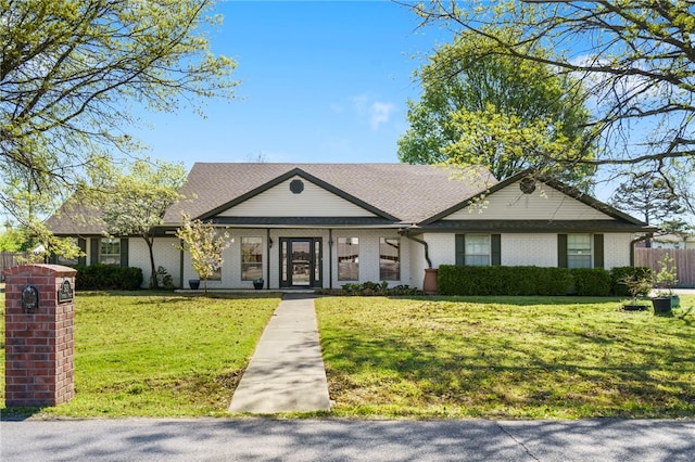 view of front facade with fence, brick siding, and a front yard