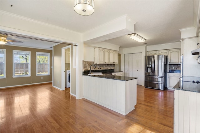 kitchen with a peninsula, stainless steel refrigerator with ice dispenser, dark wood-style flooring, and backsplash