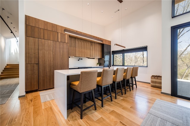 1104 N Fillmore St, Bentonville, AR 72712 - kitchen featuring an island with sink, light countertops, modern cabinets, brown cabinetry, and high vaulted ceiling