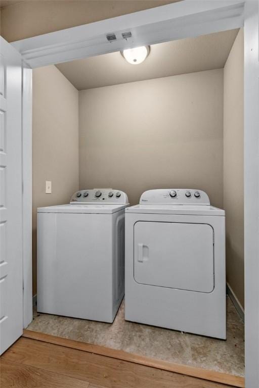 clothes washing area with laundry area, light wood-style flooring, and washer and clothes dryer