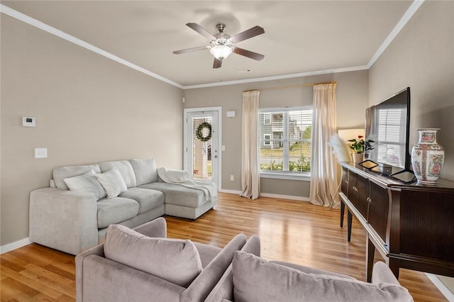 living area featuring baseboards, crown molding, and ceiling fan