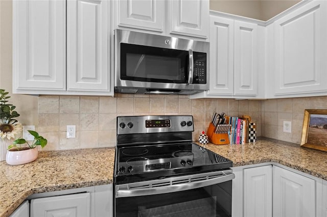 kitchen featuring white cabinets, stainless steel appliances, light stone counters, and backsplash