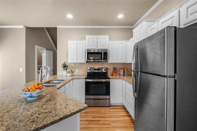 kitchen with a sink, appliances with stainless steel finishes, crown molding, and white cabinetry