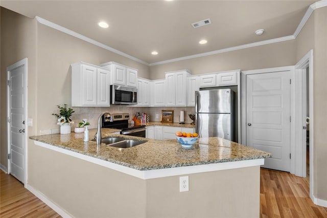 kitchen featuring stainless steel appliances, light wood-style floors, light stone counters, and a peninsula