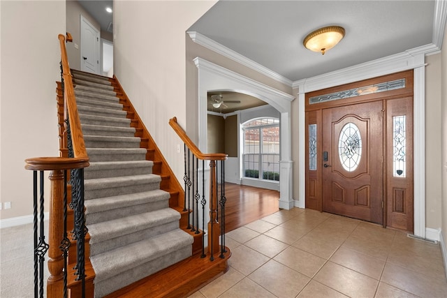 3902 NE Cadbury Ave, Bentonville, AR 72712 - foyer with crown molding, arched walkways, stairs, light tile patterned floors, and baseboards