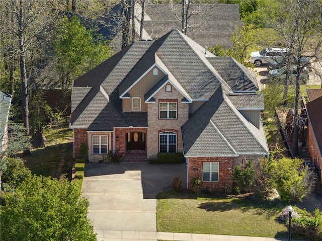 3902 NE Cadbury Ave, Bentonville, AR 72712 - view of front of house with a shingled roof, brick siding, driveway, and a front lawn