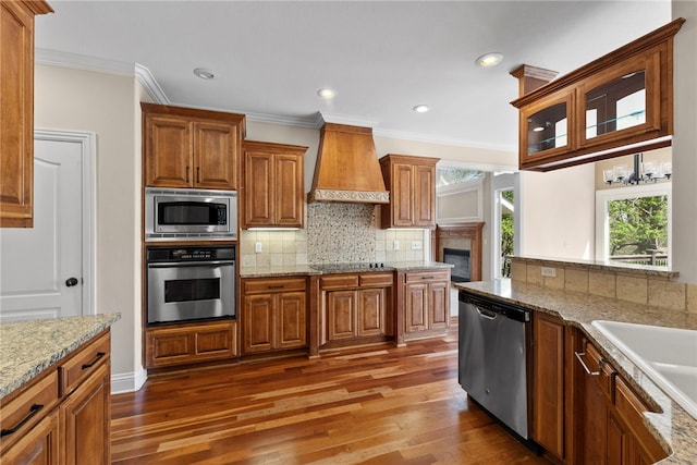 3902 NE Cadbury Ave, Bentonville, AR 72712 - kitchen with appliances with stainless steel finishes, premium range hood, wood finished floors, brown cabinetry, and crown molding