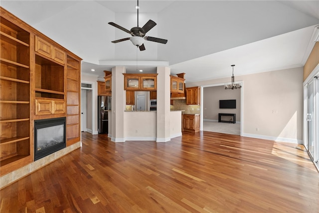 3902 NE Cadbury Ave, Bentonville, AR 72712 - unfurnished living room featuring a glass covered fireplace, a chandelier, a ceiling fan, wood finished floors, and crown molding