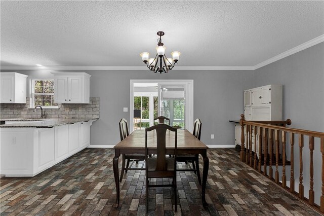 dining area with brick floors, a textured ceiling, a chandelier, ornamental molding, and baseboards