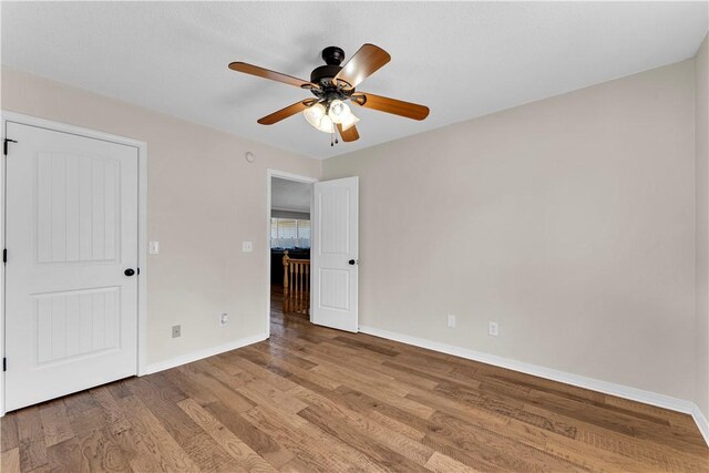 unfurnished bedroom featuring wood finished floors, baseboards, and a ceiling fan