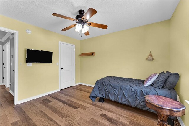 bedroom with wood finished floors, baseboards, ceiling fan, and a textured ceiling