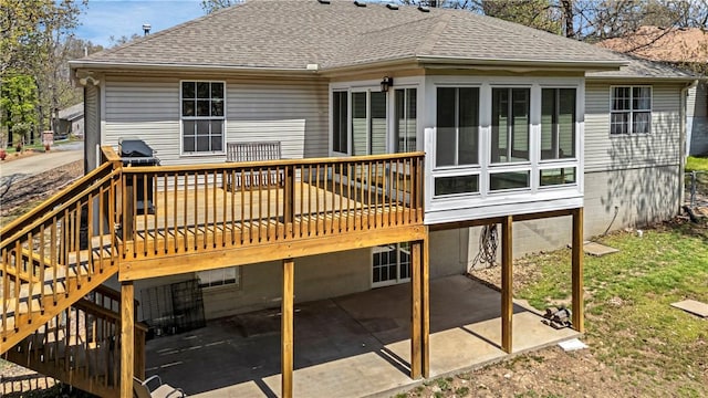 back of property featuring a sunroom, a patio, roof with shingles, a wooden deck, and stairway