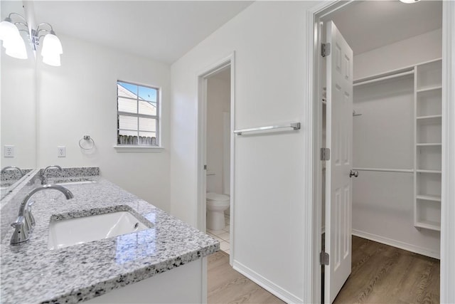 1765 Oxford Pl, Springdale, AR 72764 - bathroom with a walk in closet, toilet, a chandelier, wood finished floors, and double vanity