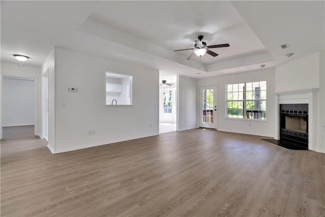 1765 Oxford Pl, Springdale, AR 72764 - unfurnished living room with ceiling fan, a tray ceiling, a fireplace with flush hearth, wood finished floors, and baseboards