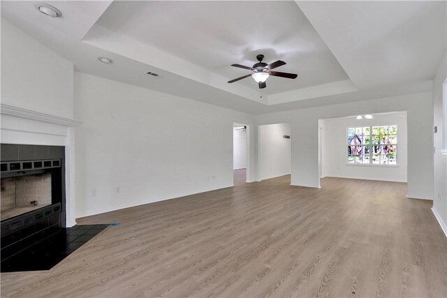 1765 Oxford Pl, Springdale, AR 72764 - unfurnished living room with a raised ceiling, a ceiling fan, wood finished floors, baseboards, and a fireplace