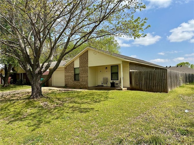 view of front of property with a garage, brick siding, a front lawn, and fence