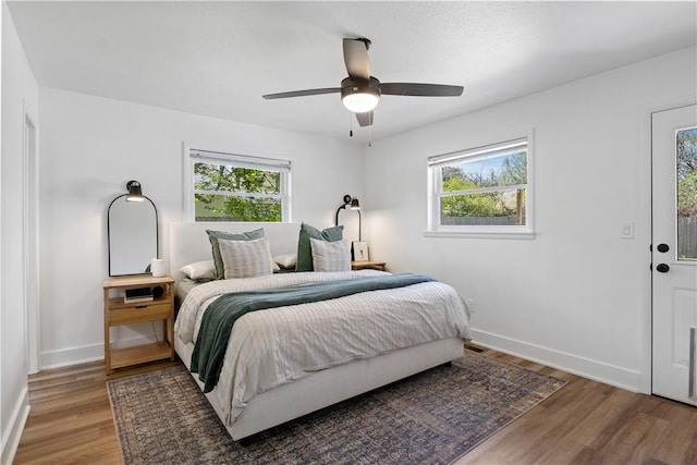 bedroom with baseboards, wood finished floors, and multiple windows
