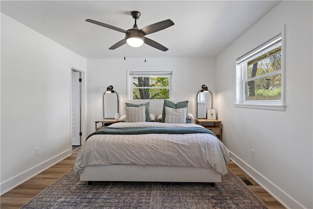 bedroom featuring visible vents, baseboards, wood finished floors, and ceiling fan
