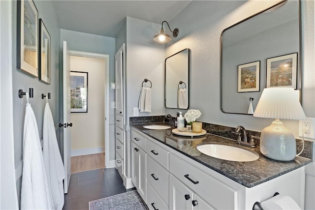 bathroom featuring tile patterned floors, baseboards, a sink, and double vanity