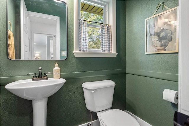 half bathroom with a textured wall and toilet