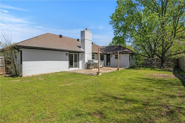 rear view of property featuring a fenced backyard, a shingled roof, a patio area, a lawn, and brick siding