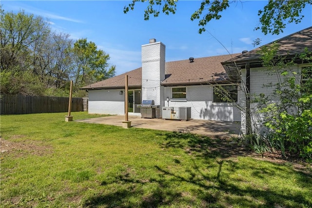 rear view of house with a lawn, central air condition unit, a chimney, fence, and a patio