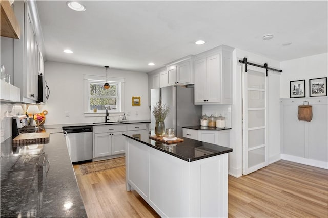 kitchen with light wood-style flooring, appliances with stainless steel finishes, white cabinetry, and a sink