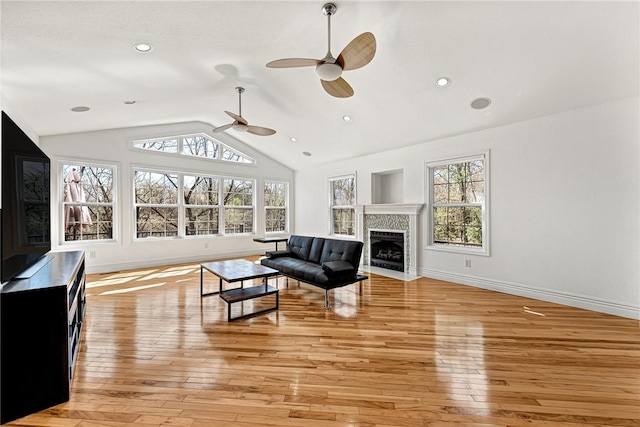 living room with vaulted ceiling, light wood-type flooring, a healthy amount of sunlight, and a ceiling fan