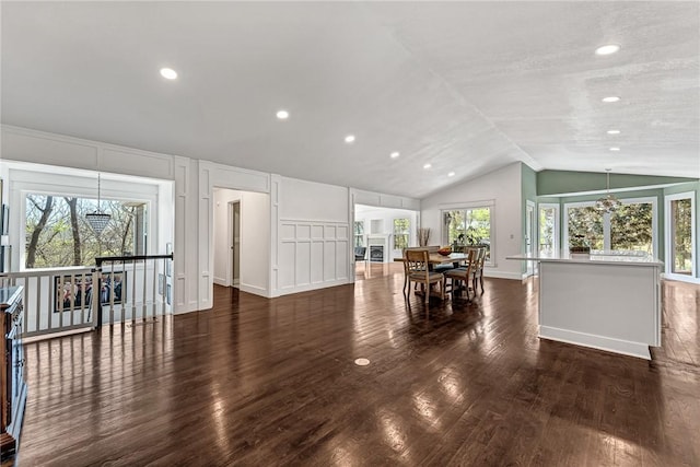 dining space with a decorative wall, lofted ceiling, wood finished floors, and recessed lighting