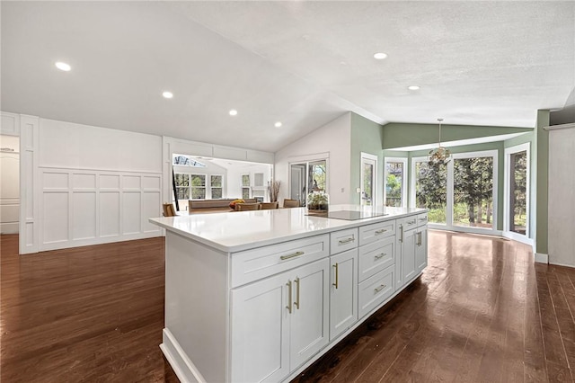 kitchen with a center island, black electric cooktop, light countertops, dark wood finished floors, and lofted ceiling