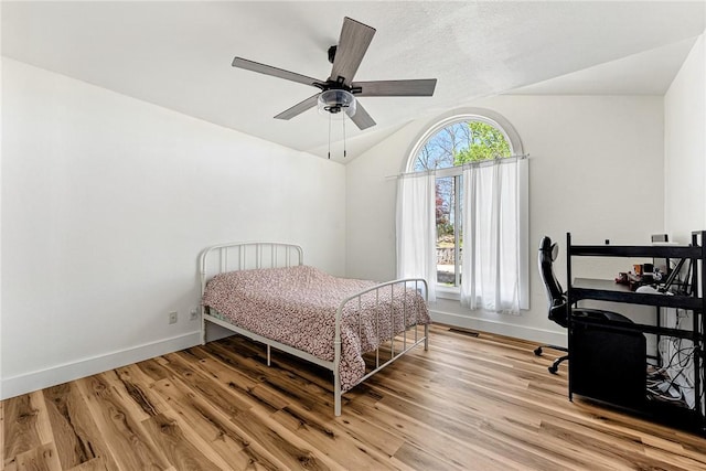 bedroom featuring vaulted ceiling, light wood finished floors, and baseboards
