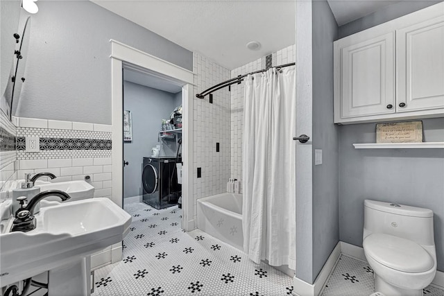 bathroom with washing machine and dryer, toilet, tile patterned floors, and shower / bath combo with shower curtain