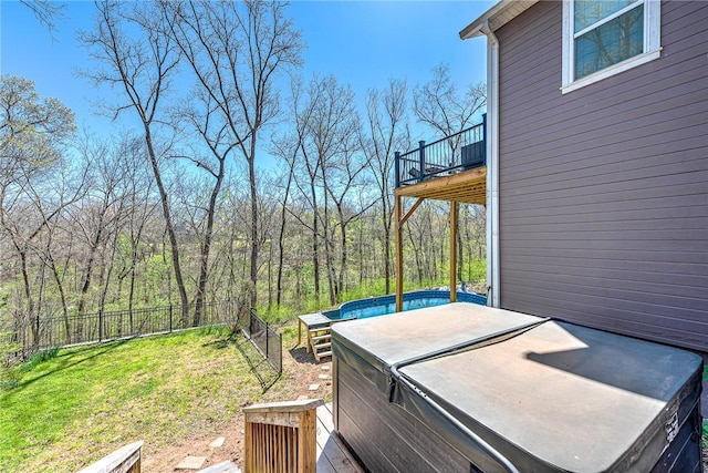 wooden terrace with a fenced backyard, a yard, a hot tub, and a wooded view
