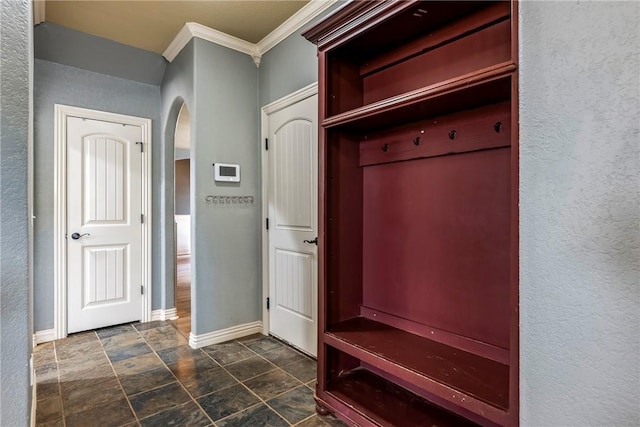 mudroom with arched walkways, ornamental molding, baseboards, and a textured wall