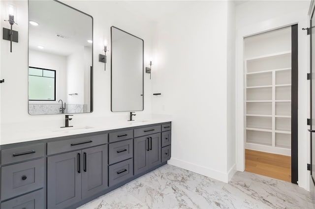 13775 Colline Rd, Bentonville, AR 72712 - bathroom featuring double vanity, a walk in closet, baseboards, and marble look tiles