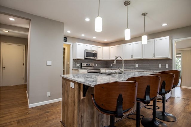 kitchen featuring tasteful backsplash, appliances with stainless steel finishes, white cabinetry, and a sink