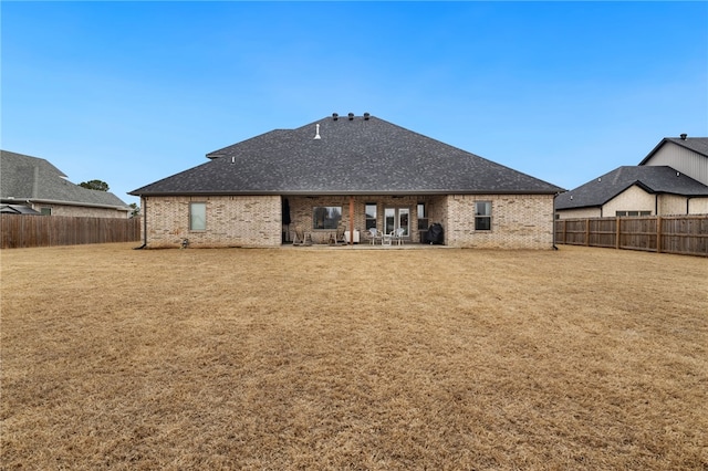 rear view of property featuring a fenced backyard, a yard, a patio area, and brick siding