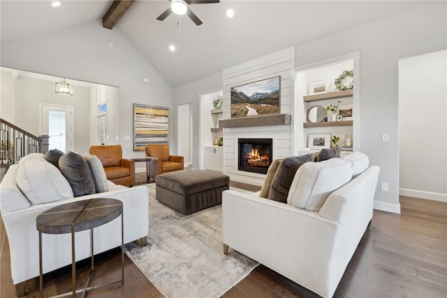 living room with wood finished floors, ceiling fan, beam ceiling, and a fireplace