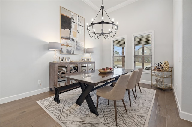 dining area featuring baseboards, ornamental molding, wood finished floors, and a notable chandelier