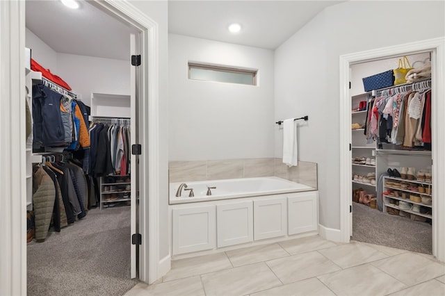 bathroom with recessed lighting, a spacious closet, and a bath