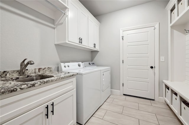 laundry room with baseboards, a sink, cabinet space, and washer and dryer
