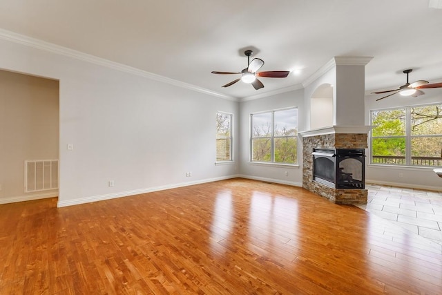 unfurnished living room with a ceiling fan, a wealth of natural light, and visible vents