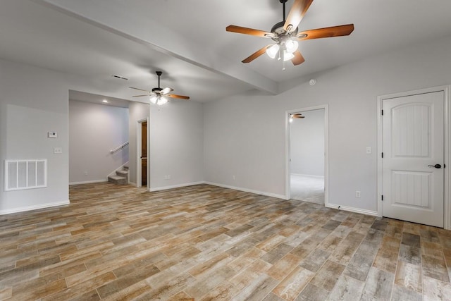 spare room featuring light wood finished floors, visible vents, ceiling fan, and stairway