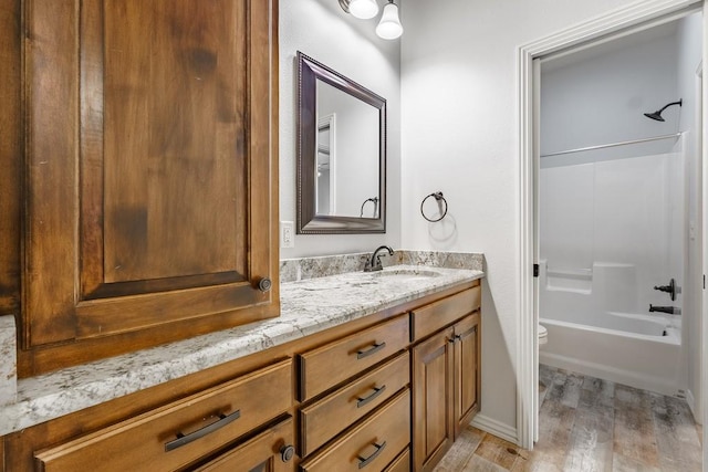 bathroom featuring toilet, wood finished floors, vanity, and shower / bath combination
