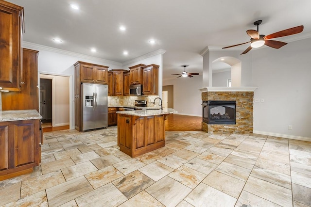 kitchen featuring a peninsula, crown molding, a ceiling fan, baseboards, and appliances with stainless steel finishes