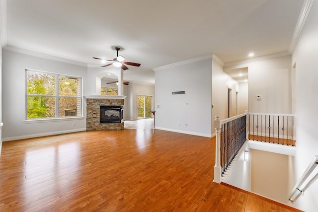 unfurnished living room featuring baseboards, ornamental molding, ceiling fan, wood finished floors, and a fireplace