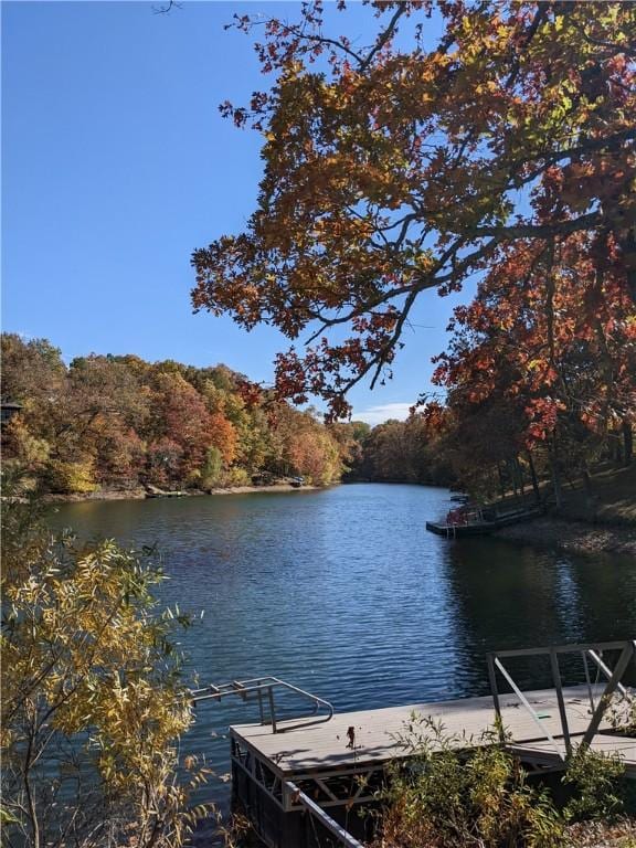 view of dock featuring a wooded view and a water view