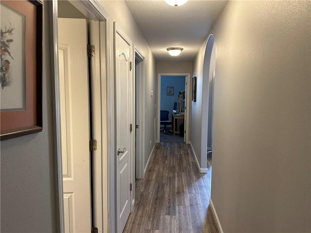 hall featuring baseboards and dark wood-style flooring
